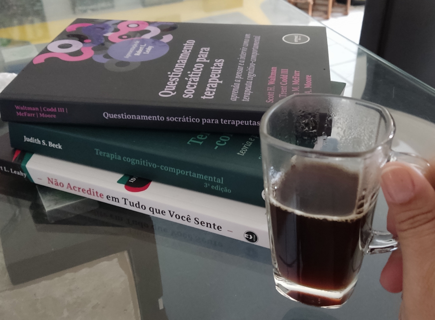 Livros de Terapia Cognitivo-Comportamental e uma xícara de café
